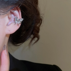 Macro shot of silver butterfly ear cuff with zircon tassels worn on the ear bone