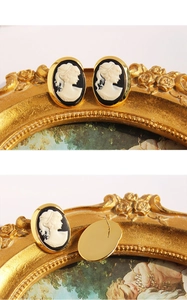 Close-up of vintage cameo earrings with golden metal frames and portrait relief detail