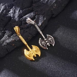 Punk style skull axe pendants in gold and silver finish on a dark rock surface