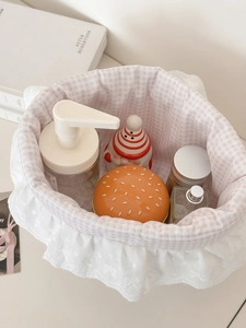 Detailed top view of pink gingham storage basket with white lace trim and desk items