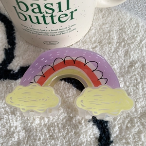 Detail of a colorful acrylic hair claw clip in a rainbow and yellow cloud design shape