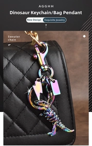 Rainbow metal dinosaur skeleton keychain hanging on a black quilted leather handbag