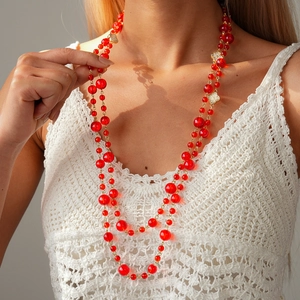 Close-up of multi-layer red beaded sweater necklace with golden crystal flower pendants