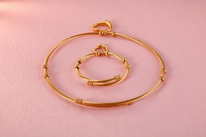 Detailed view of the gold twisted cable necklace and matching heart charm bracelet