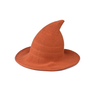 Close-up detail of a bright orange knitted witch hat featuring a unique pointed top