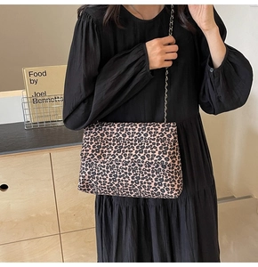 Detail of leopard print flap bag with gold chain strap worn by a model in a retro setting