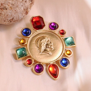 Macro detail of vintage gold brooch featuring cameo relief and multicolored gemstones