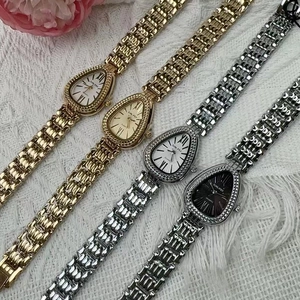 Detailed close-up of gold and silver snake-shaped quartz watches on white textured fabric