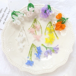 Handmade colorful beaded flower pendants for DIY jewelry making in a ceramic dish