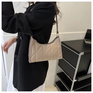 Chic quilted beige hobo bag with diamond pattern shown on a woman shoulder in an office