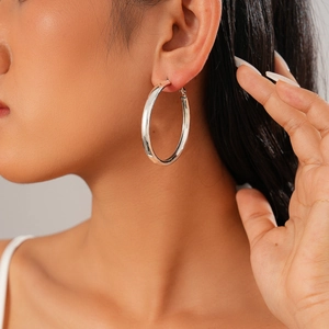 Close-up of a silver polished geometric hoop earring on a model for a classic look