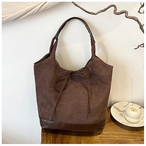 Detail of the brown suede tote bag with leather straps in a minimalist vintage setting