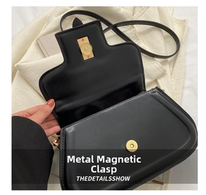 Detail of the high-quality gold magnetic clasp on a black leather minimalist handbag