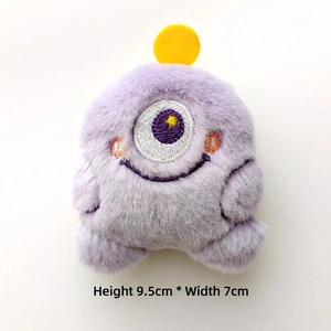 Detail view of a purple plush monster charm with embroidery measuring 9.5cm by 7cm