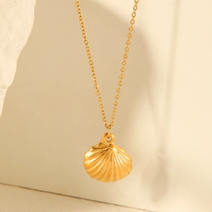 Detailed close-up of a gold scallop shell pendant on a dainty stainless steel chain