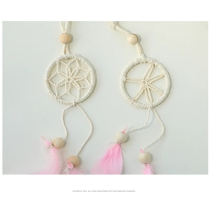 Macro detail of handmade dreamcatcher wall hanging with pink feathers and wooden beads