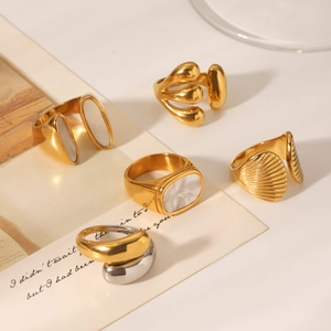 Detail shot of golden rings with shell inlay and bicolor designs on minimalist background