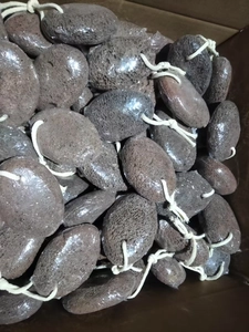 Bulk brown volcanic lava pumice stones with white hanging ropes in a storage box