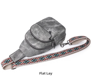Detail of grey crossbody bag with colorful ethnic style woven strap and zippers