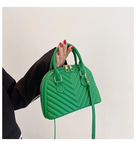 Detail of green shell bag featuring V-shaped quilting and elegant gold metal hardware
