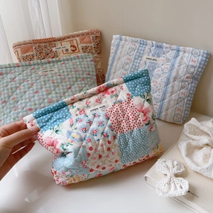 Close-up of quilted floral and plaid cotton pouches featuring the Simple Wish fabric label