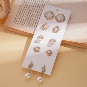 Set di cinque orecchini in lega dorata con perle e strass su un libro decorativo