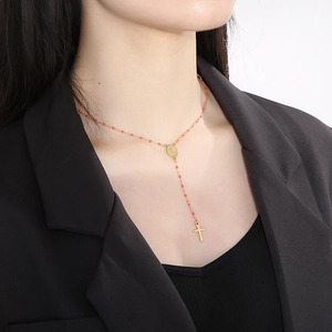 Detail of gold rosary necklace with pink beads, Virgin Mary medal and cross pendant