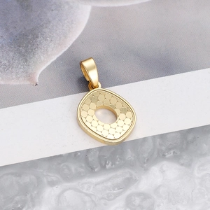 Macro shot of gold letter O pendant featuring circular scale texture and metallic finish