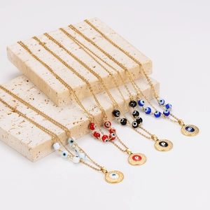 Golden stainless steel necklaces with evil eye pendants in various colors on travertine
