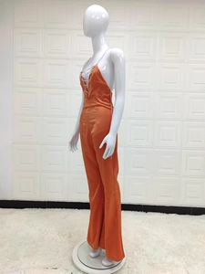 Detail of orange satin jumpsuit featuring deep V-neck and silver chain halter strap