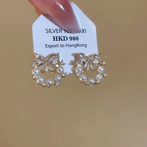 Macro detail of 925 silver bow earrings with sparkling crystals and white pearls