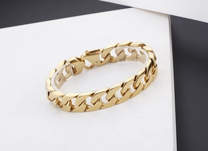 Détail d'un bracelet gourmette doré épais avec une finition en métal poli et son fermoir