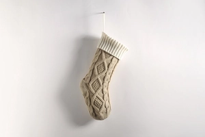Detail of beige knit Christmas stocking featuring classic diamond and cable patterns