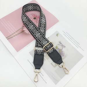 Close-up of geometric jacquard shoulder strap with golden metal buckles and leather ends