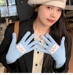 Detail of light blue knitted gloves with a white fabric label featuring red text