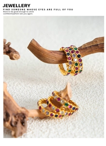 Artistic close-up of a gold titanium ring with multicolored cubic zirconia on a wood branch