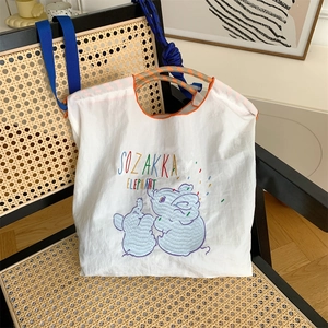 Close-up of cute elephant embroidery and orange stitching on white oxford tote bag