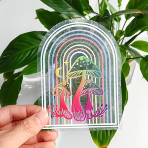 Rainbow mushroom suncatcher window decal with prismatic laser effect shown against nature