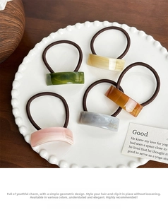Close-up of five acetate ponytail holders with marble textures on a white lace plate
