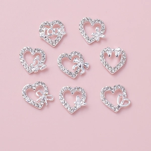 Close-up of silver alloy heart nail art charms with sparkling rhinestones and bow designs