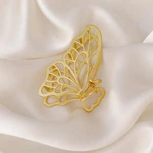 Detail of elegant hollow butterfly hair claw clip in polished gold alloy finish