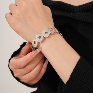 Detailed view of a silver-colored embossed floral pattern bracelet on a female wrist