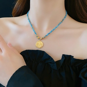 Ethnic style blue beaded necklace with a gold eye pendant and colorful gemstone inlay