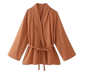 Detailed view of caramel jacquard wrap top with belted waist and long sleeves