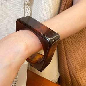 Detailed view of square resin bangle featuring glossy amber tortoise shell pattern