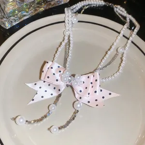 Elegant multi-layer pearl necklace with a pink polka dot bow and sparkling crystal pendant