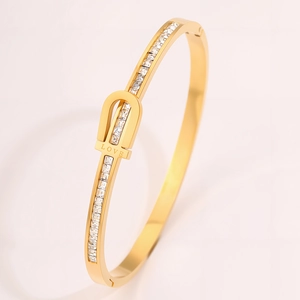 Detail of gold horseshoe bangle featuring pave zircons and LOVE engraving on the clasp