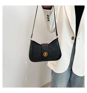Détail du sac sous le bras à paillettes noires avec fermoir doré sur veste blanche
