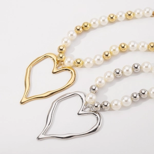 Macro detail of mixed pearl bead necklace featuring an irregular hollow heart pendant