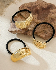 Detailed close-up of gold hair ties featuring wavy, twisted, and hammered textures
